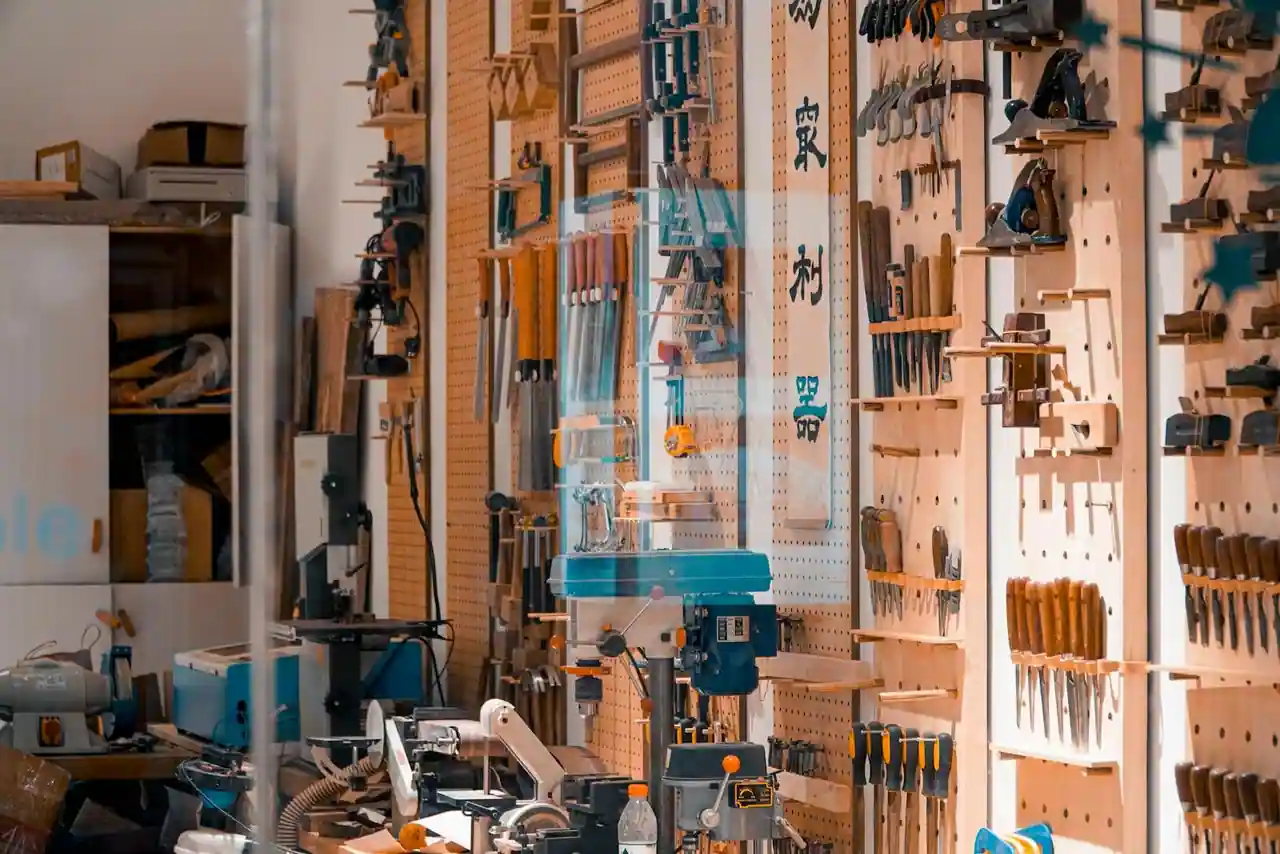 Établi de bricolage avec outils manuels rangés, perceuse et matériaux dans un garage lumineux