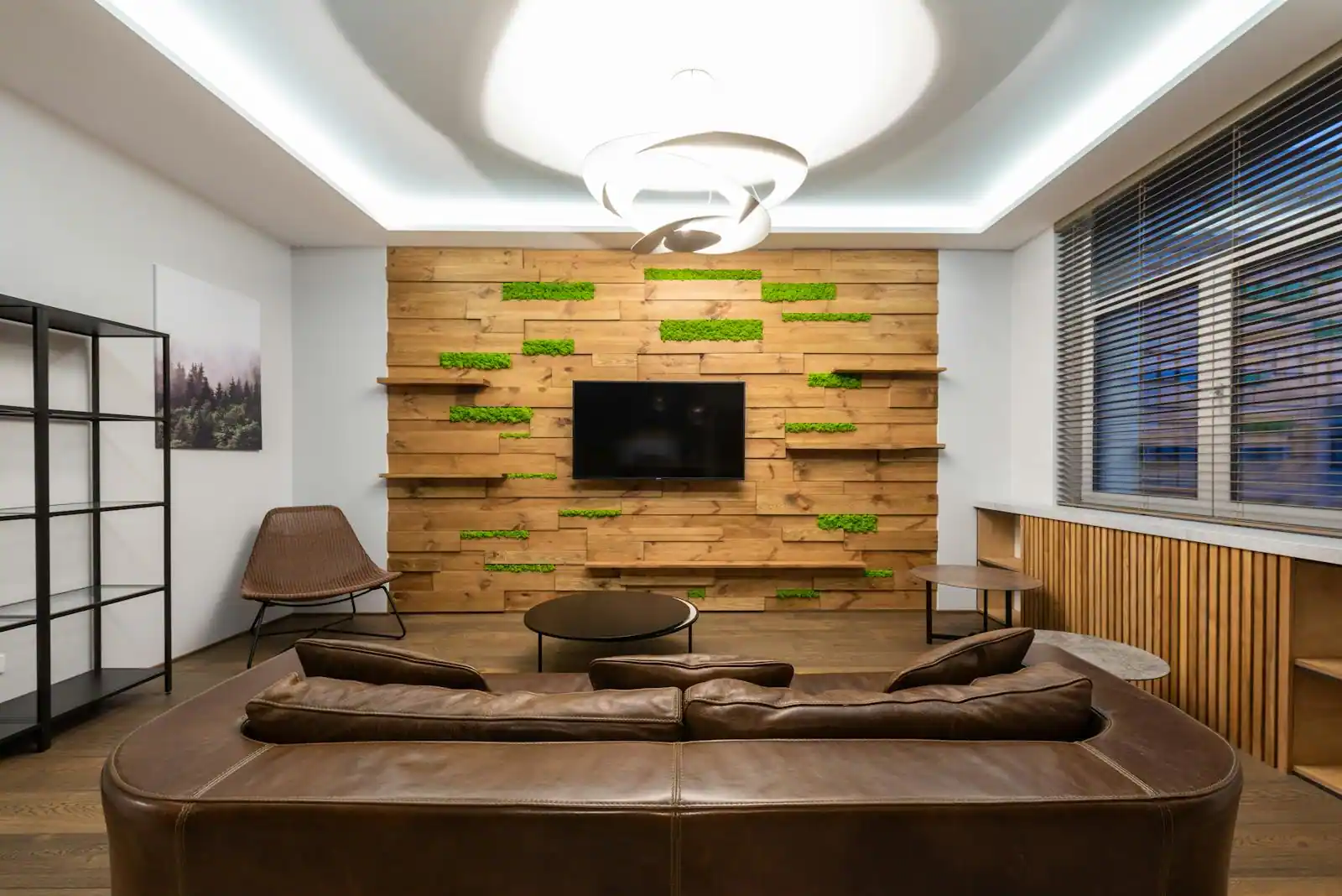 Salon contemporain avec mur d'accent peint en vert sauge profond, canapé en lin et bibliothèque en bois clair, lumière douce du matin