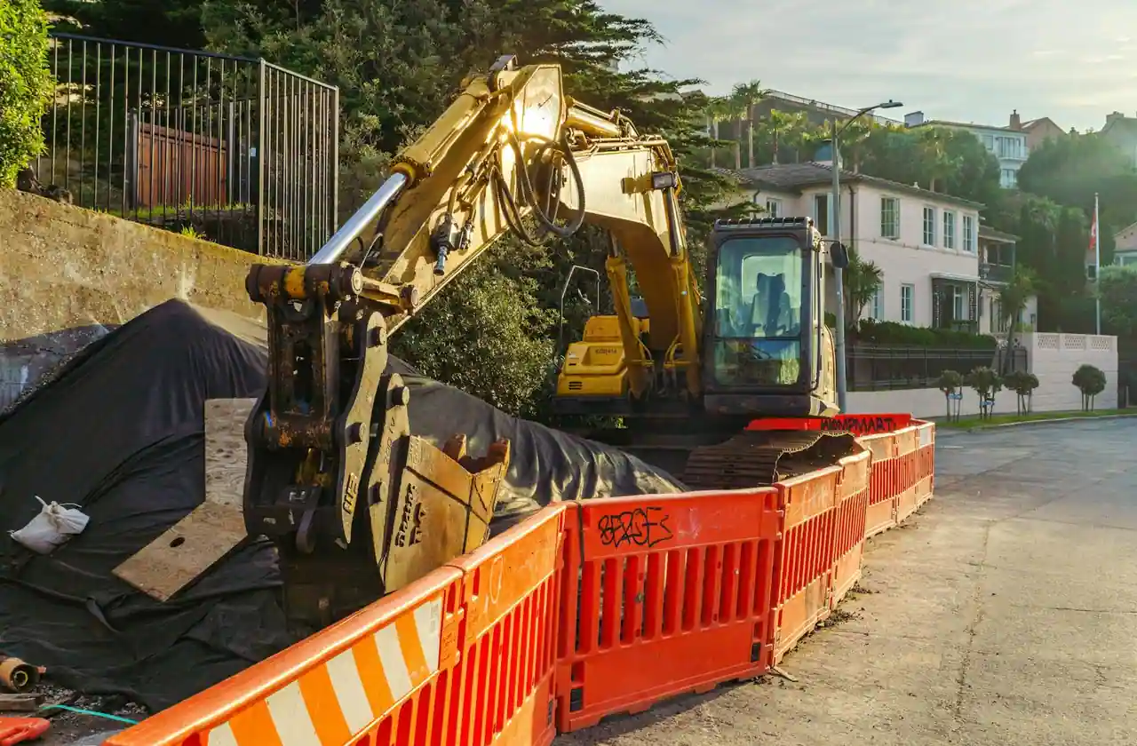 Mini-pelle compacte en chantier particulier creusant une tranchée de jardin