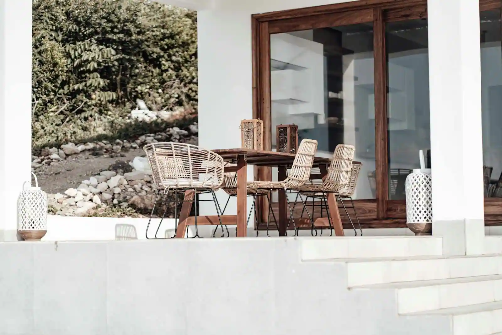 Table de jardin en acacia dressée sur une terrasse en bois, fauteuils pliants assortis et lumière de fin de journée