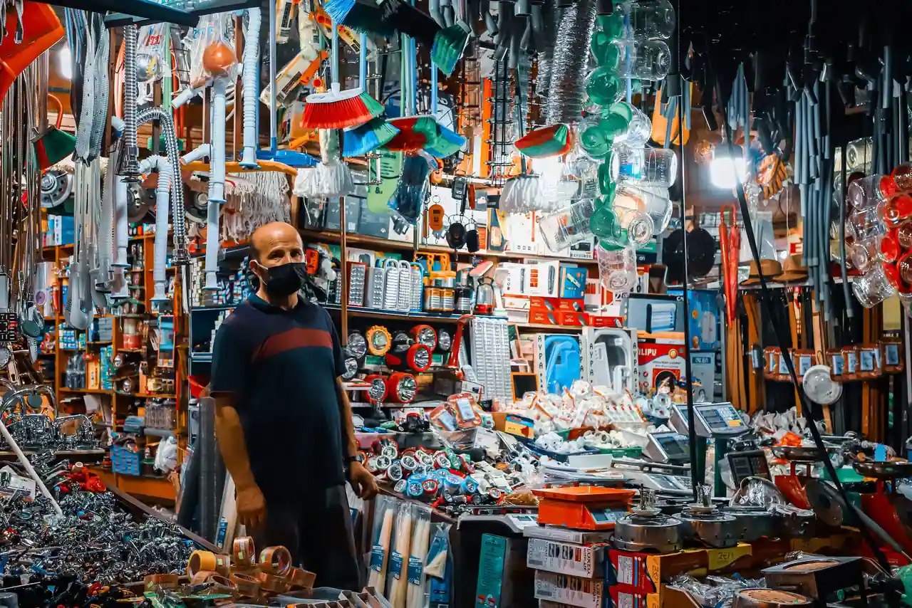 Rayon d'outils et de quincaillerie dans un grand magasin de bricolage, avec un client qui compare des produits.