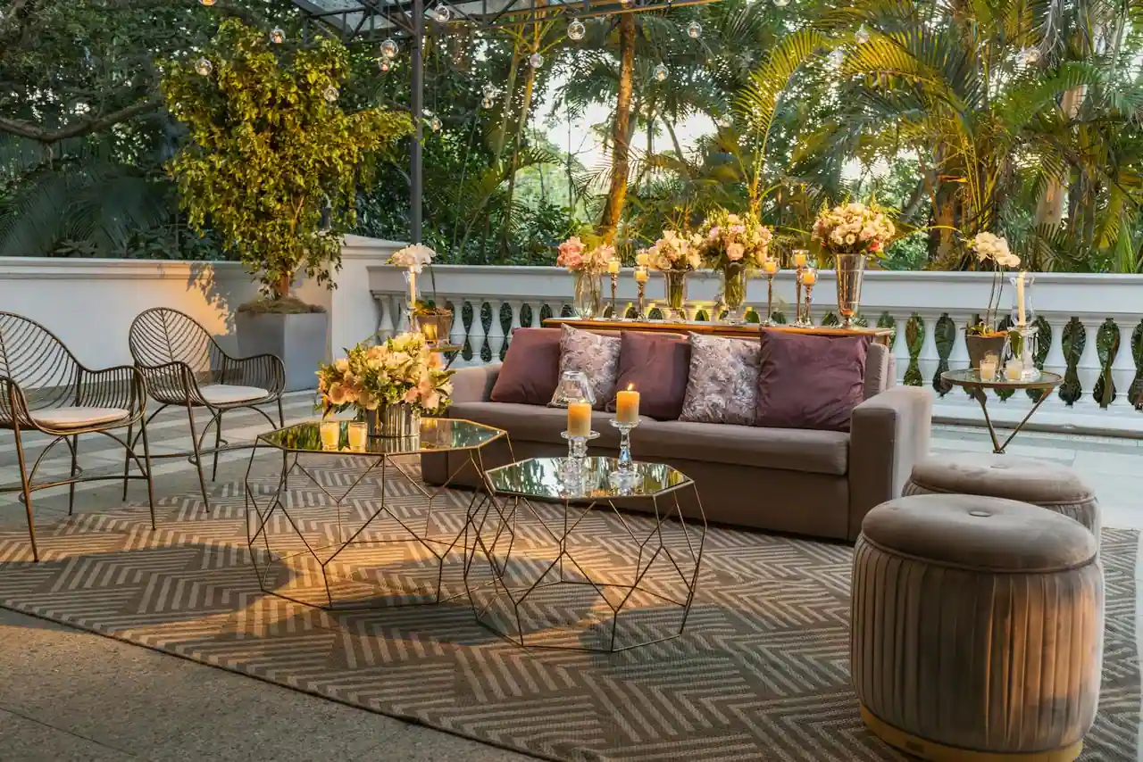 Canapé garni de coussins installé sur une terrasse extérieure, avec tables basses, fauteuils et tapis