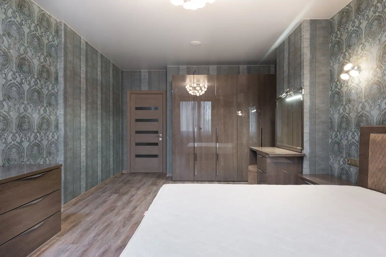 Chambre lumineuse au mobilier clair et fonctionnel, lit, armoire et table de chevet harmonisés