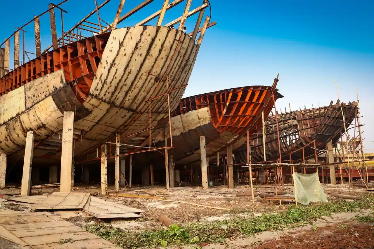 Coques de bateaux en bois en construction dans un chantier naval, étayées sur des piliers