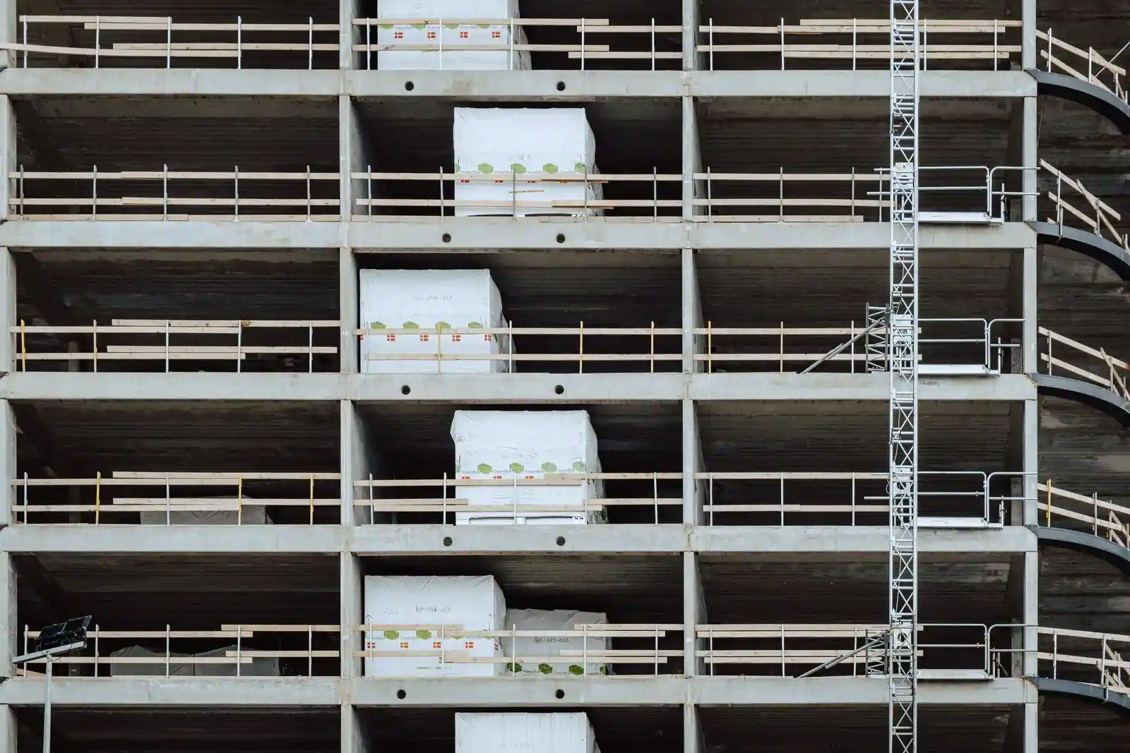 Immeuble en construction, planchers de béton à étages avec garde-corps et matériaux stockés