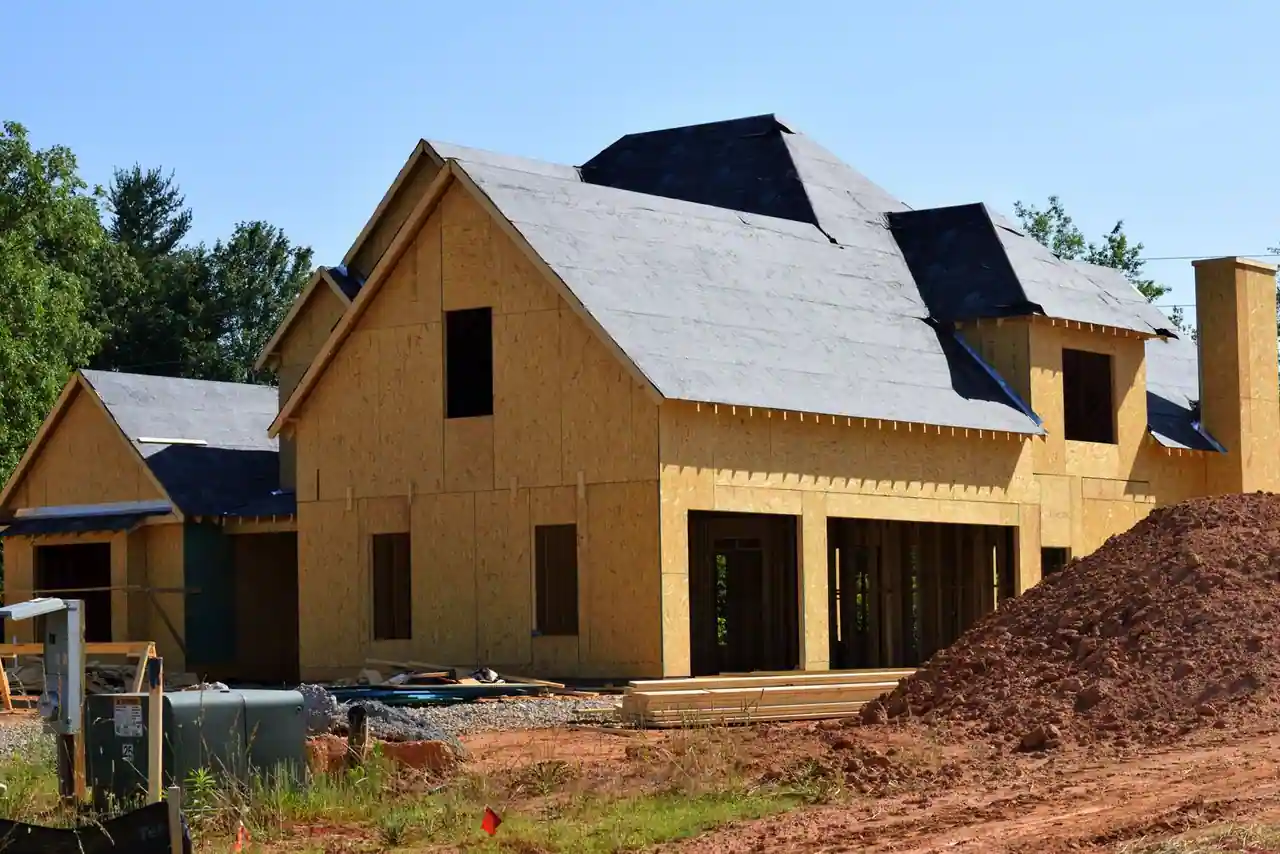 Maison individuelle en cours de construction, ossature et toiture posées, avant la pose des menuiseries.