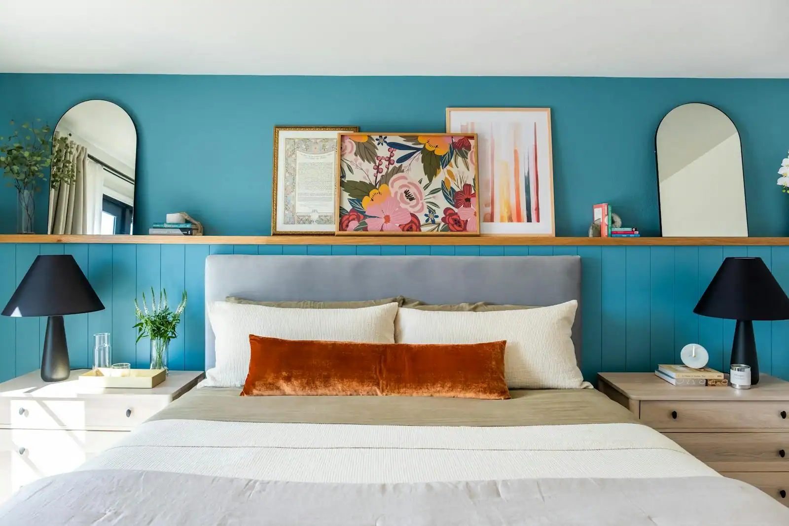 Mur de chambre d'adulte habillé d'une composition de cadres au-dessus de la tête de lit