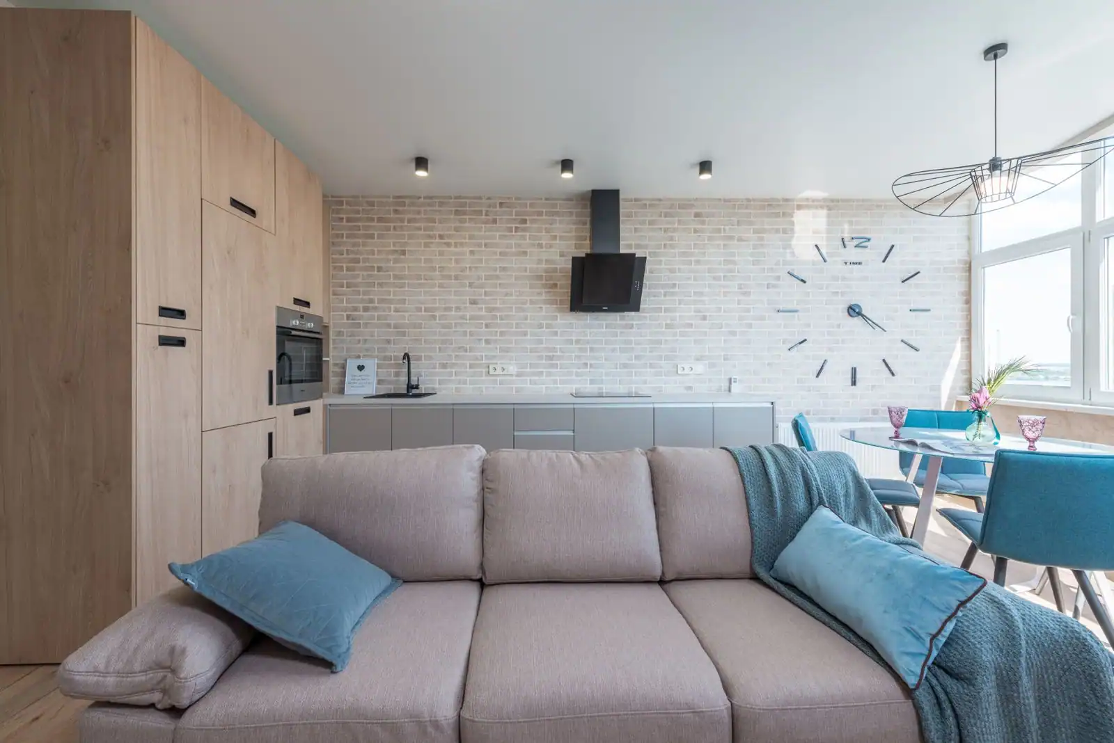 Intérieur d'un logement meublé lumineux avec canapé, coin cuisine équipé et table à manger