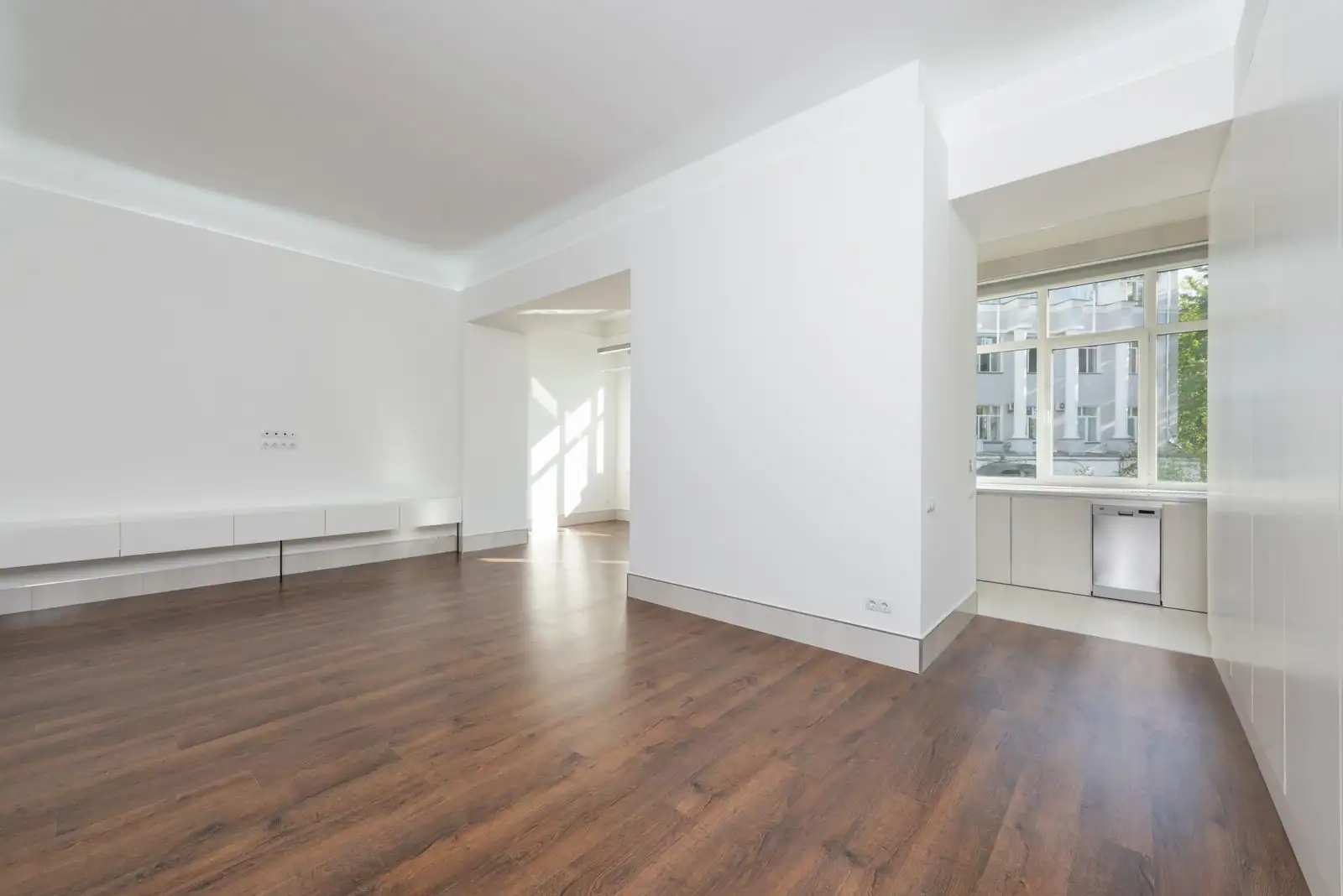Salon lumineux d'un appartement vide aux murs clairs et au parquet, prêt à être loué.