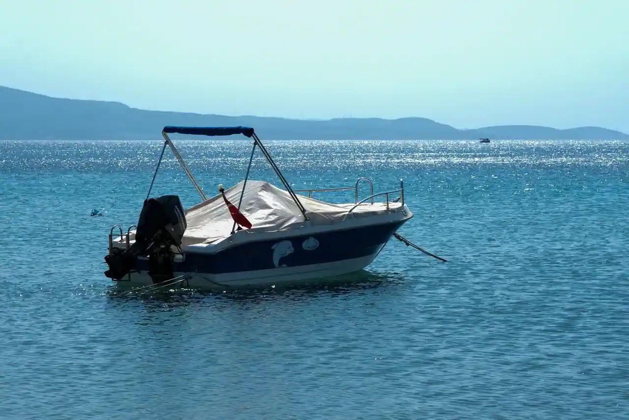 Petit bateau à moteur de plaisance amarré sur une mer bleue calme, prêt pour une sortie