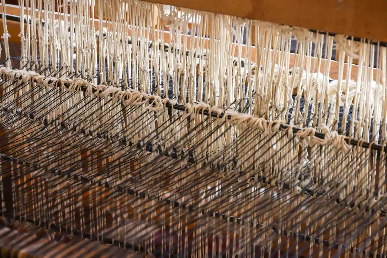 Métier à tisser ancien dans un atelier de manufacture, avec des fils tendus pour une tapisserie en cours