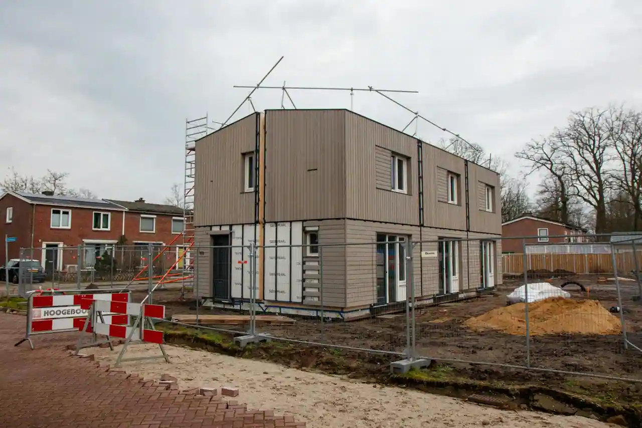 Maison individuelle en cours de construction avec grue et échafaudages sur un chantier résidentiel par temps clair.