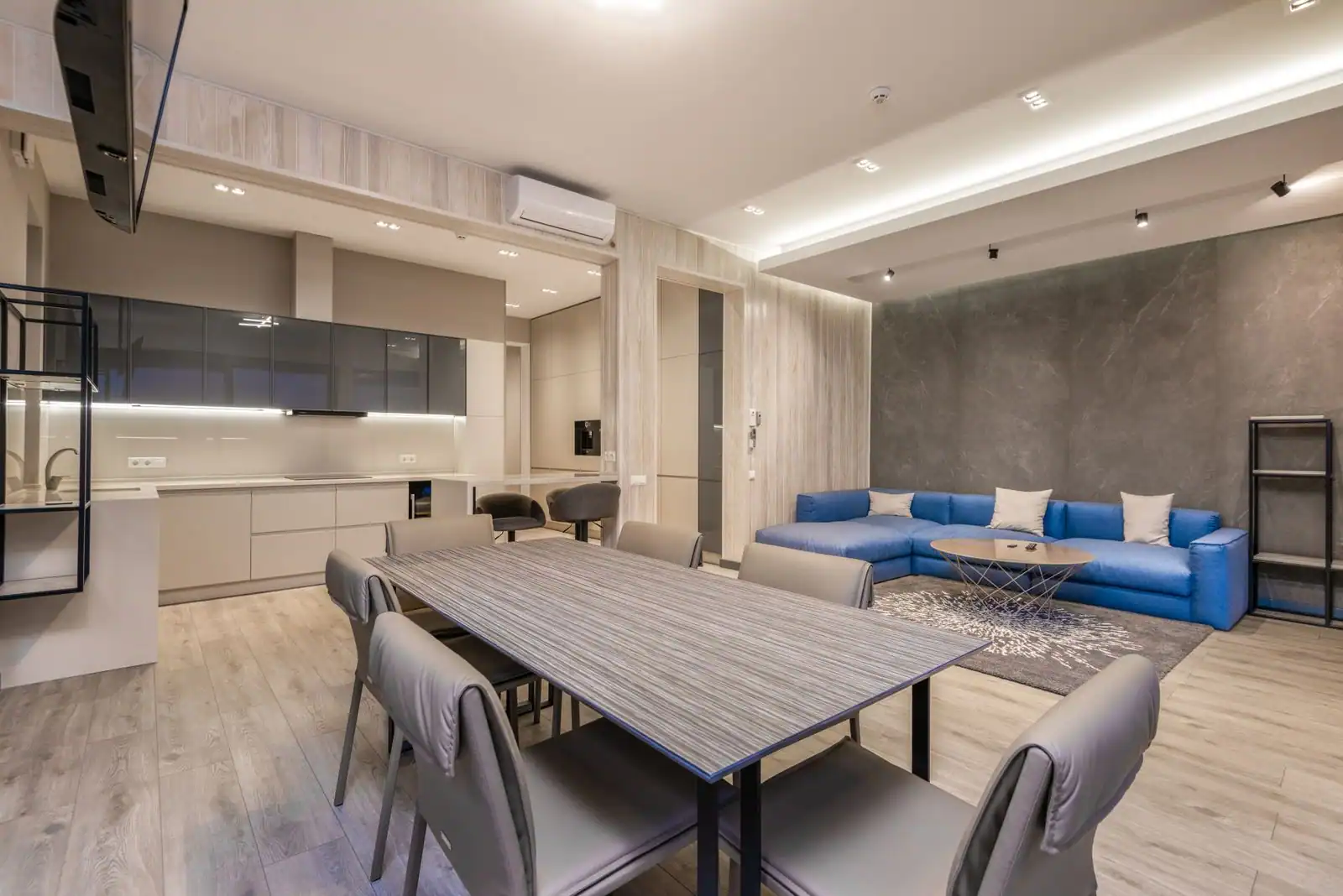Intérieur d'un appartement meublé avec coin salon, table à manger et cuisine équipée.