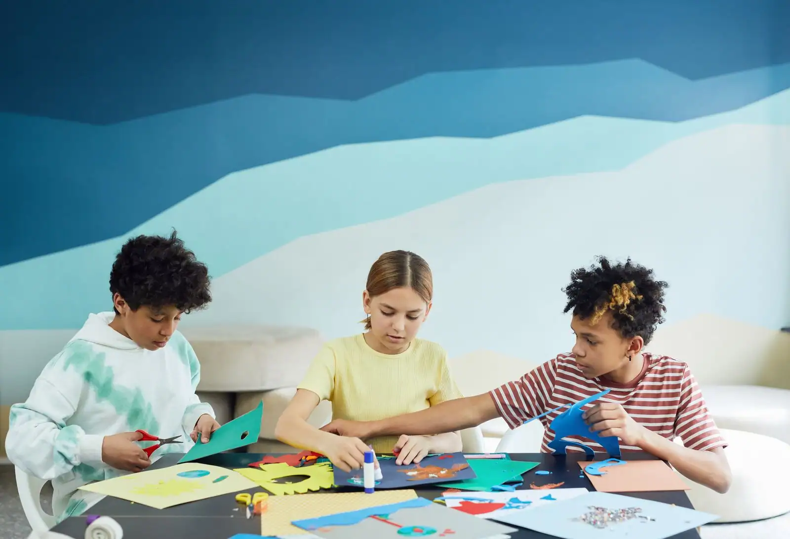 Enfant fabriquant un masque de carnaval coloré avec papier, feutres et plumes