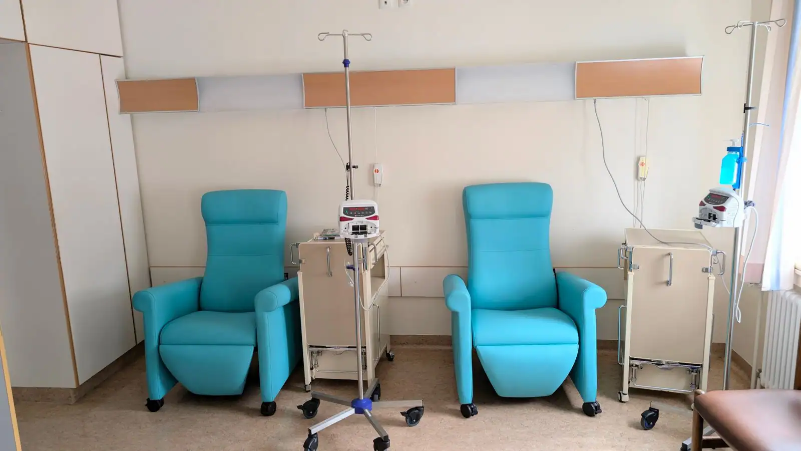 Salle de traitement hospitalière avec fauteuils de soin et pieds à sérum équipés de pompes à perfusion.
