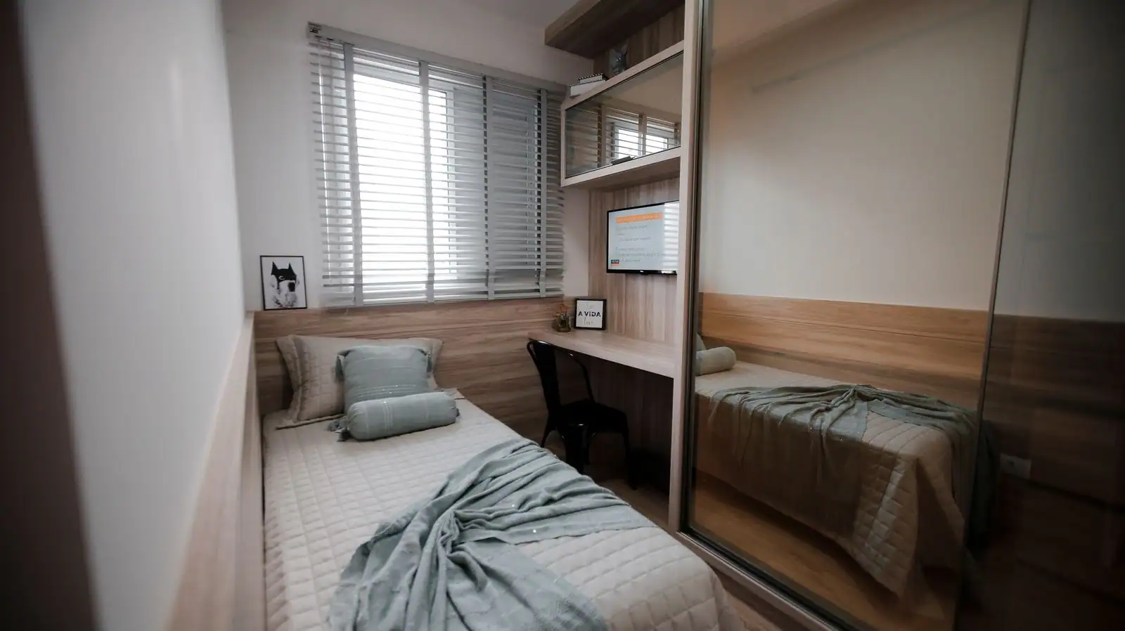 Une petite chambre avec un lit simple, un bureau et des rangements, aménagée pour optimiser l’espace.