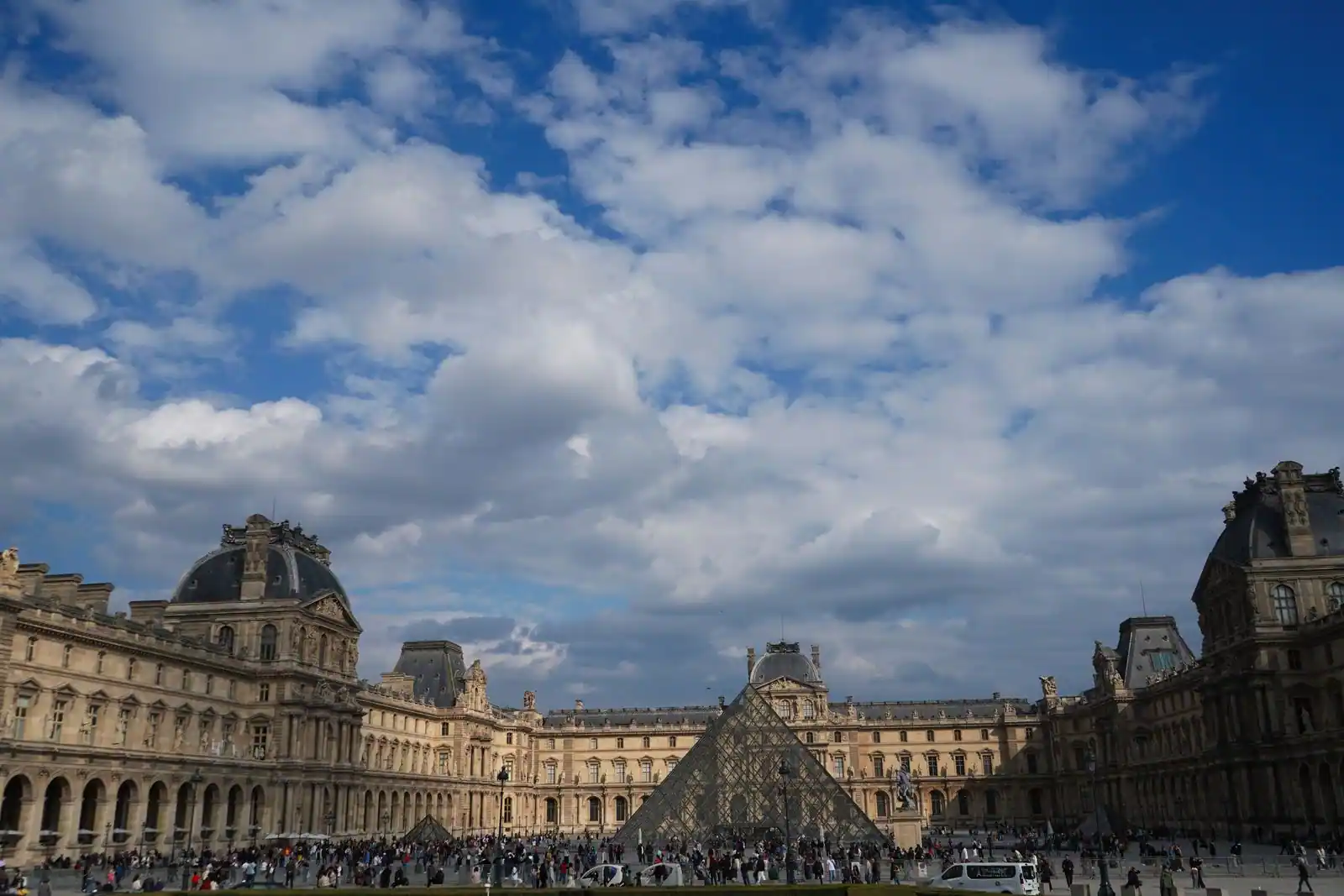 La pyramide de verre du Louvre au centre de la cour Napoléon, à Paris, sous un ciel clair.