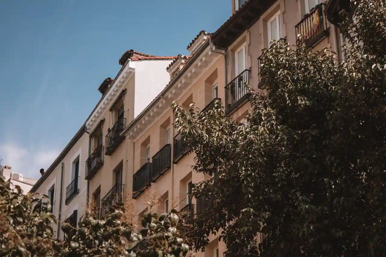 Façades d'immeubles résidentiels avec balcons en fer forgé le long d'une rue arborée.