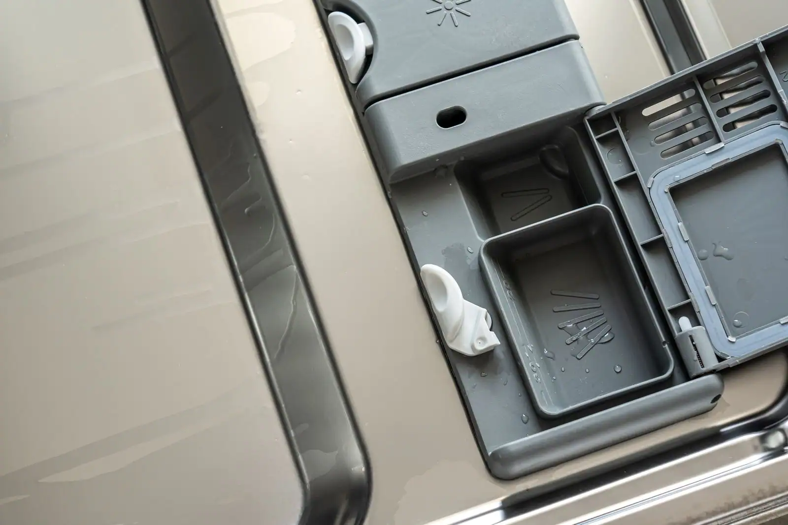 Personne versant du liquide de rinçage dans le bac de la porte d'un lave-vaisselle