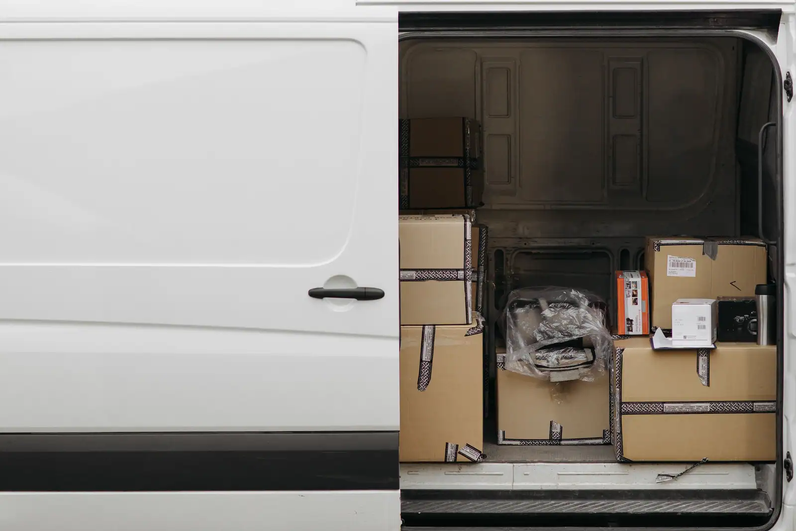 Un fourgon utilitaire blanc, porte latérale ouverte, chargé de cartons prêts pour le transport.