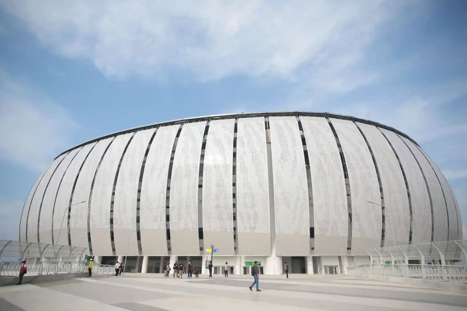 Grande enceinte sportive moderne vue de l’extérieur, parvis et spectateurs, image illustrative