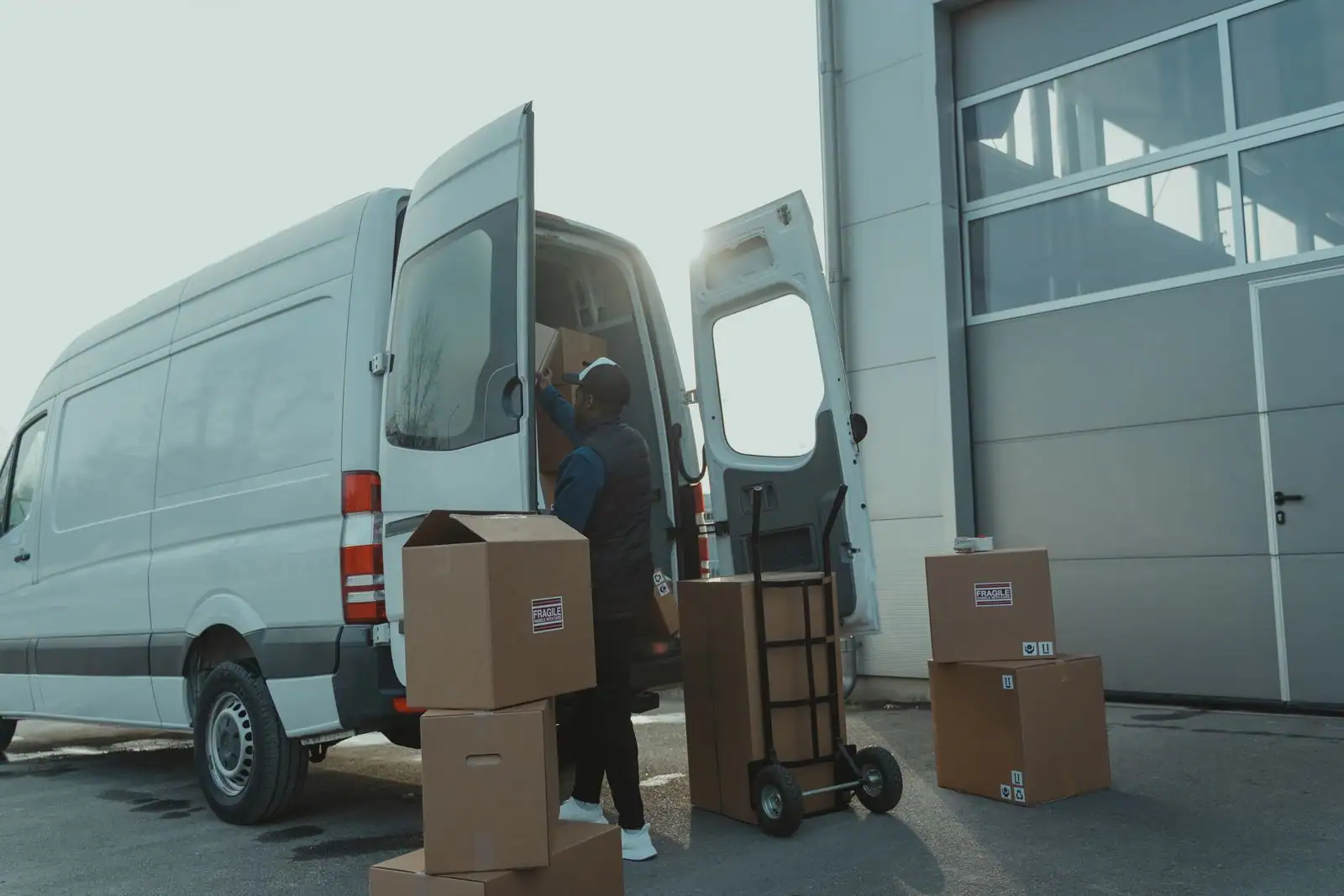 Un fourgon utilitaire blanc aux portes arrière ouvertes, chargé de cartons pour un déménagement.