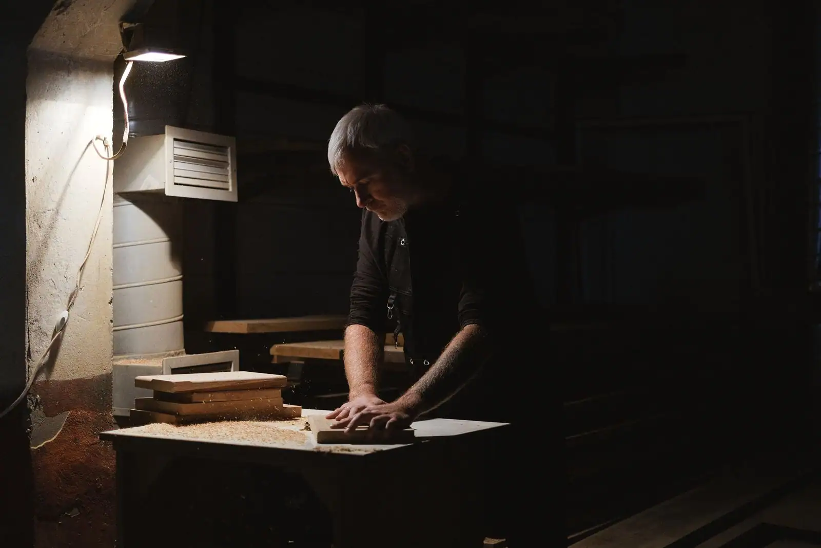 Menuisier façonnant un meuble en bois dans un atelier, plan de travail et outils de menuiserie.