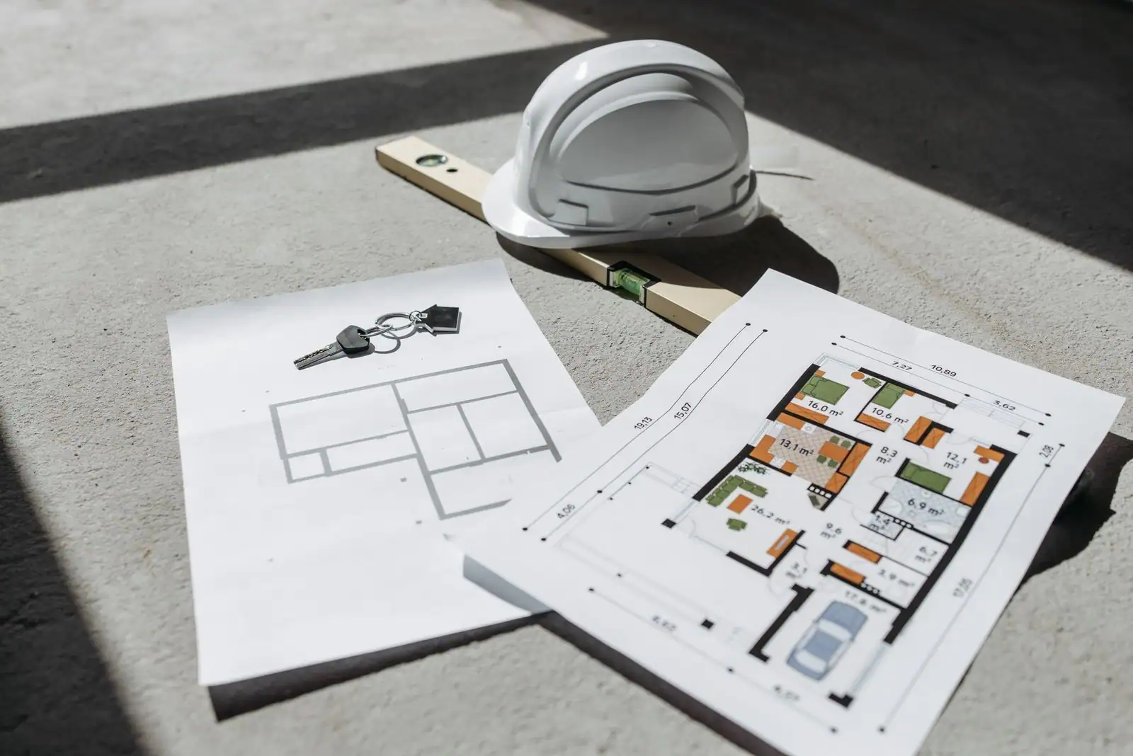 Plans d'architecte d'une maison, casque de chantier et niveau posés au sol sur un chantier