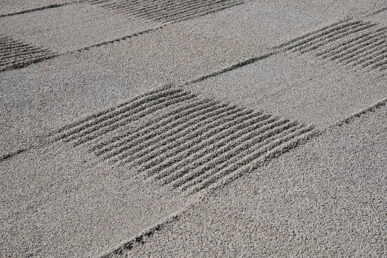 Gravier clair finement ratissé en motifs géométriques, caractéristique d'un jardin zen minéral japonais.