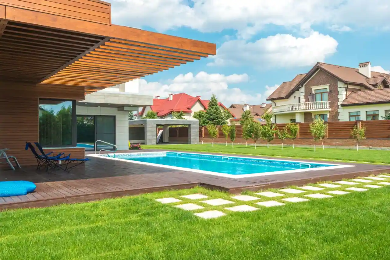 Piscine extérieure enterrée bordée d'une terrasse dans un jardin verdoyant