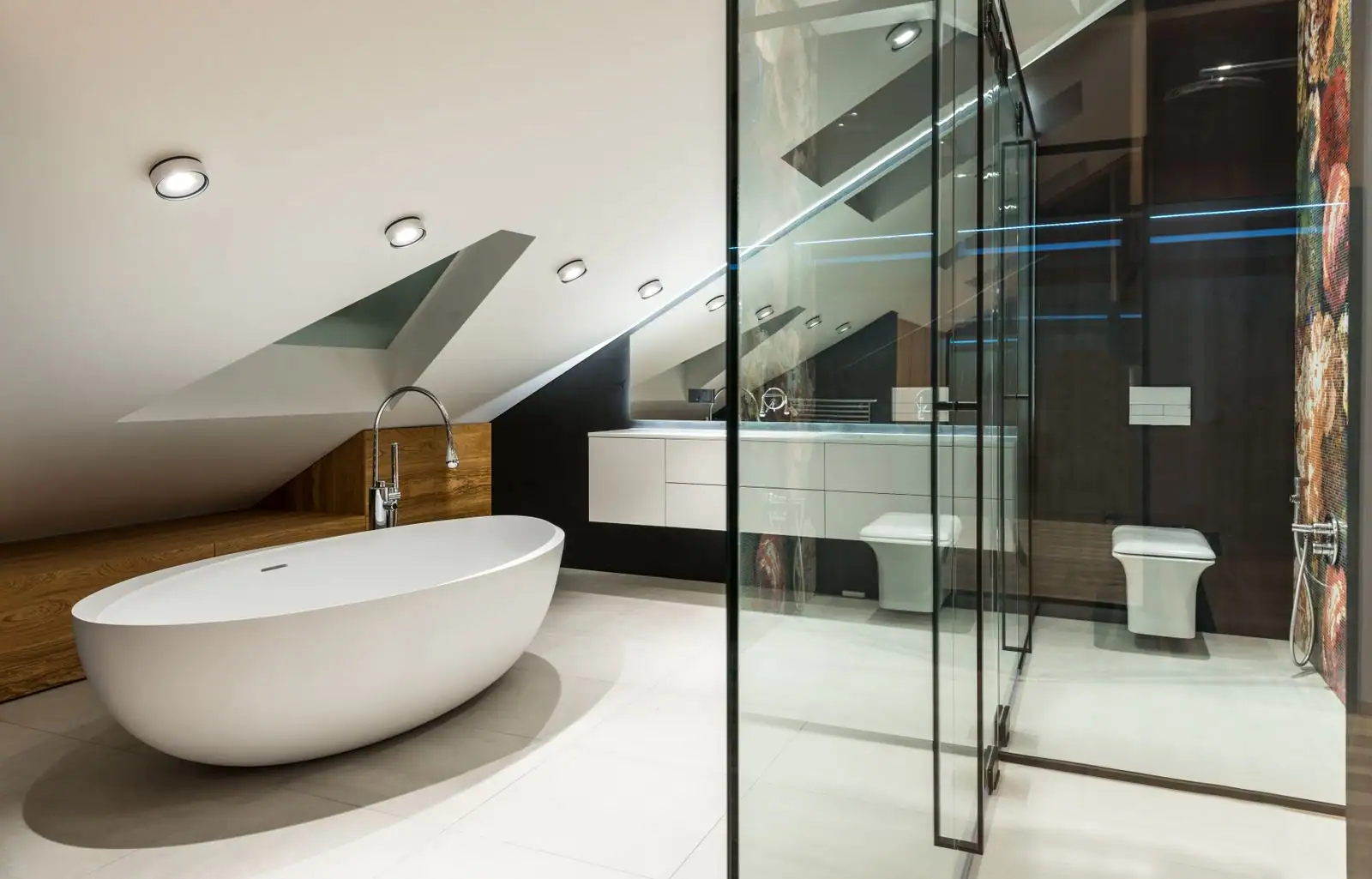 Salle de bain aménagée sous une pente de toit avec fenêtre de toit et baignoire