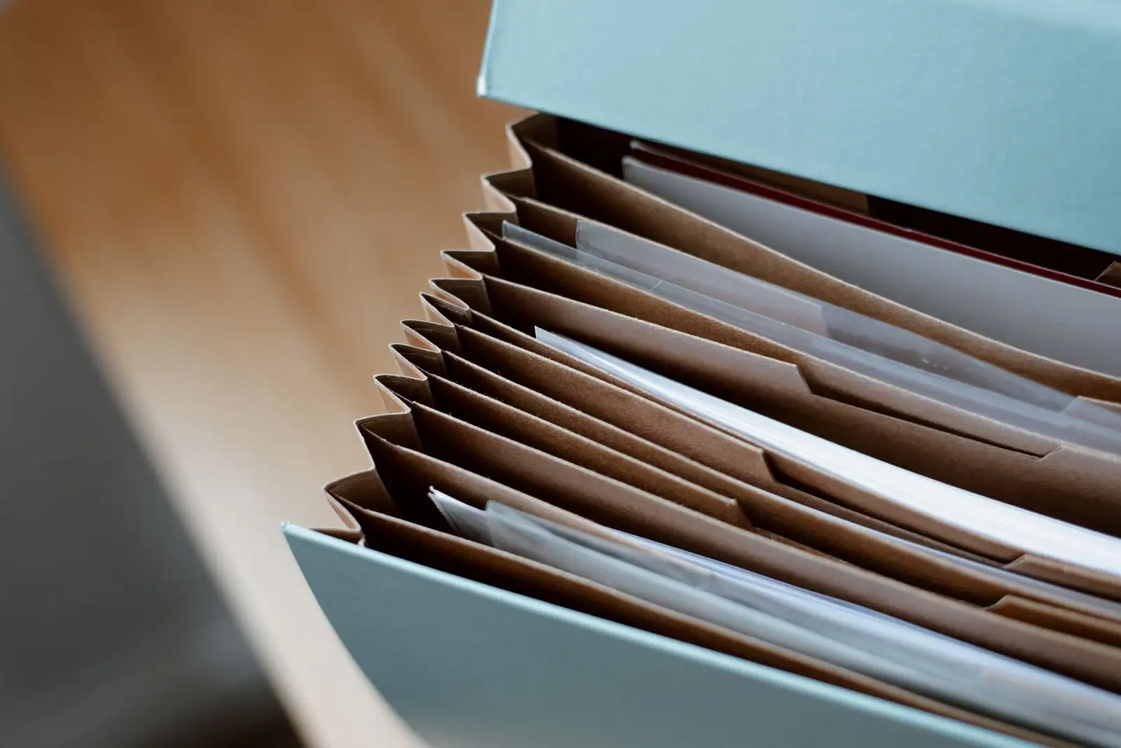 Trieur à soufflets garni de documents administratifs, posé sur un plan de travail en bois clair.