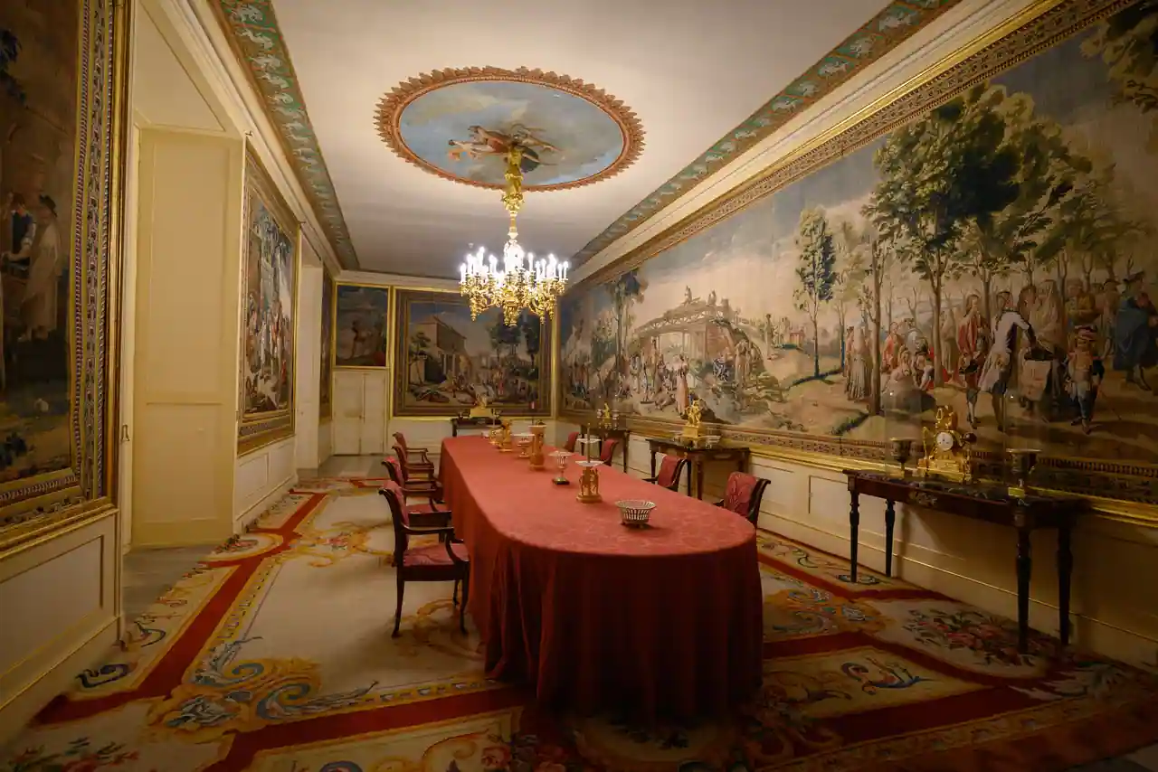 Tapisseries murales, tapis et sièges anciens dans une salle d'apparat aux consoles dorées