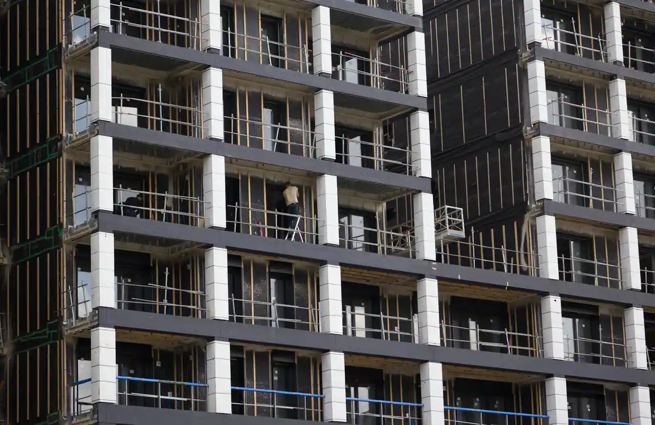Façade d'un immeuble de logements collectifs en chantier, balcons bruts et ouvriers au travail